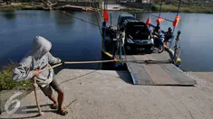 Pekerja menarik perahu eretan berisi kendaraan menyebrangi Sungai Citarum di Muara Gembong, Bekasi, Rabu, (29/7/2015). Kendaraan yang menyebrang menggunakan perahu eretan dikenakan biaya Rp.20.000 bagi mobil dan Rp 2.000 motor. (Liputan6.com/Johan Tallo)