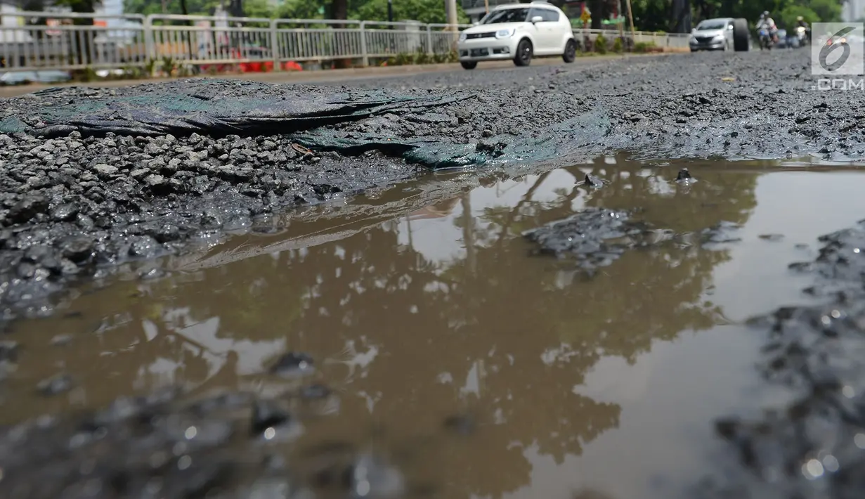 Kondisi jalan berlubang yang masih tergenang air di ruas Jalan Lapangan Ros, Tebet, Jakarta, Sabtu (11/5/2019). Jalan-jalan berlubang yang terisi air tersebut dapat mengakibatkan kecelakaan bagi pengendara kendaraan bermotor. (merdeka.com/Imam Buhori)