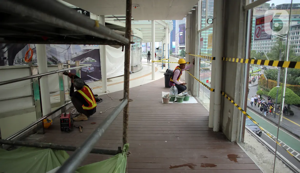 Pekerja menyelesaikan pengerjaan anjungan Halte Transjakarta Bundaran HI saat uji coba anjungan itu di kawasan Bundaran Hotel Indonesia, Jakarta, Senin (10/10/2022). Anjungan yang berada di lantai dua Halte Transjakarta Bundaran HI ini dapat menampung 20 orang. (Liputan6.com/Johan Tallo)