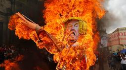 Para pengunjuk rasa membakar patung karakter Presiden AS Donald Trump saat melakukan aksi protes pada peringatan Hari Buruh di Bogota, Kolombia (1/5). Mereka melakukan aksi dengan membakar patung Donald Trump. (AP/Fernando Vergara)