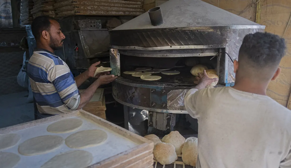 Pria Mesir memanggang roti di sebuah pasar di Kairo, pada 17 Maret 2022. Melonjaknya harga roti yang dipicu oleh invasi Rusia ke Ukraina telah menggigit daya beli konsumen di Mesir, importir gandum terkemuka dari negara-negara bekas Soviet. (Khaled DESOUKI / AFP)