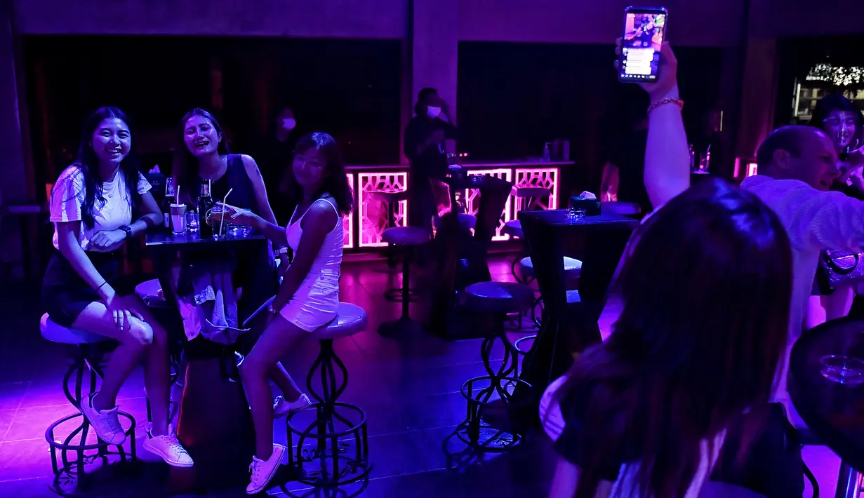 Pengunjung mendengarkan musik di bar kawasan hiburan Patpong, Bangkok, Thailand, Rabu (1/7/2020). Mulai 1 Juli, bar di Bangkok kembali diizinkan buka setelah pengurangan pembatasan untuk menghentikan penyebaran virus corona COVID-19. (Lillian SUWANRUMPHA/AFP)
