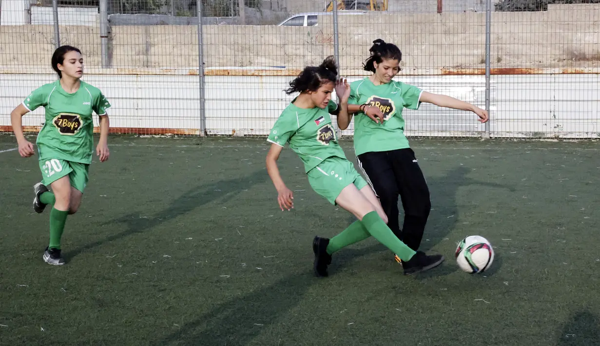 Dua pesepak bola putri klub Beit Umar Palestina berebut bola saat mengikuti sesi latihan di sebuah lapangan di Kota Hebron. (AFP/Hazem Bader)