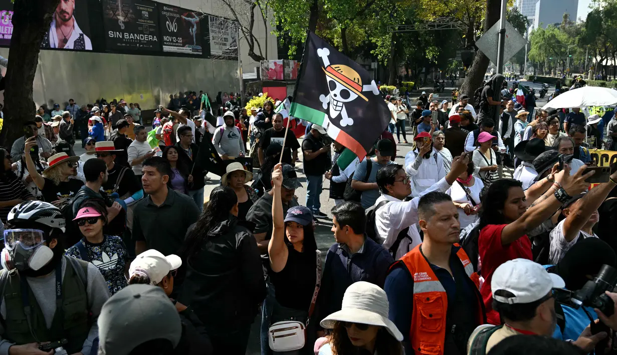 Seorang pengunjuk rasa memegang bendera berlogo manga populer Jepang, One Piece, simbol yang diadopsi oleh gerakan protes Gen Z di seluruh dunia, dalam sebuah demonstrasi yang diserukan oleh Generasi Z untuk menentang pemerintahan Presiden Meksiko, Claudia Sheinbaum, di sepanjang Reforma Avenue di Mexico City pada 20 November 2025. Ratusan demonstran muda dari gerakan Gen Z kembali turun ke jalan di Mexico City, pada Kamis 20 November 2025. (Yuri CORTEZ/AFP)