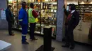 Pelanggan menunggu pembukaan kembali toko minuman keras ketika Afrika Selatan mencabut larangan penjualan alkohol dan rokok di Johannesburg, Selasa (18/8/2020). Pembelian alkohol dan rokok dilarang ketika Afrika Selatan memberlakukan lockdown ketat pada 27 Maret 2020. (AP Photo/Denis Farrell)