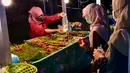 <p>Penjual melayani pembeli selama bulan suci Ramadhan di pasar malam di provinsi Narathiwat, Thailand selatan (21/4/2022). Penjual makanan jalanan mendirikan kios mereka untuk menjual makanan kepada umat Muslim untuk berbuka puasa. (AFP/Madaree Tohlala)</p>