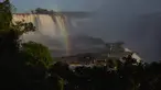 Pengunjung berjalan di sepanjang jalan setapak saat pelangi muncul di depan sebagian pemandangan Air Terjun Devil's Throat, bagian dari sistem Air Terjun Iguazu di Sungai Iguazu di Taman Nasional Iguacu, Negara Bagian Parana, dekat Foz do Iguacu di Brasil selatan yang berbatasan dengan Argentina, saat matahari terbenam pada 21 Mei 2024. (Mariana SUAREZ / AFP)