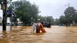Seorang perempuan berjas hujan mengarungi jalanan yang tergenang banjir di Hue pada 28 Oktober 2025. Ribuan warga dievakuasi setelah curah hujan lebih dari 1.000 milimeter (mm) dalam 24 jam terakhir yang membanjiri kota di wilayah tengah Vietnam itu. (Foto oleh AFP)