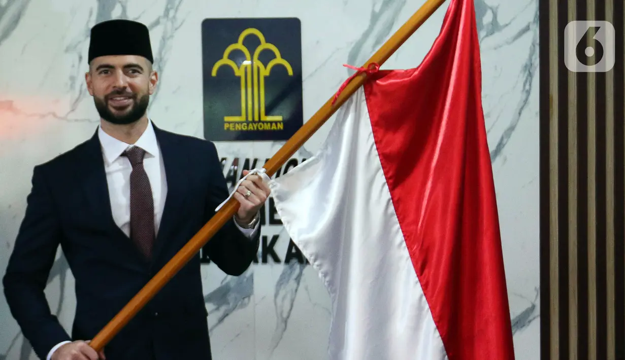 Pemain sepak bola Jordi Amat memegang bendera Merah Putih usai menjalani Sumpah Janji Setia Pewarganegaraan di Kantor Wilayah Kementerian Hukum dan HAM DKI Jakarta, Kamis (17/11/2022). Jordi Amat resmi menjadi Warga Negara Indonesia (WNI) setelah prosesi pengambilan sumpah yang digelar secara tertutup. (Liputan6.com/Herman Zakharia)
