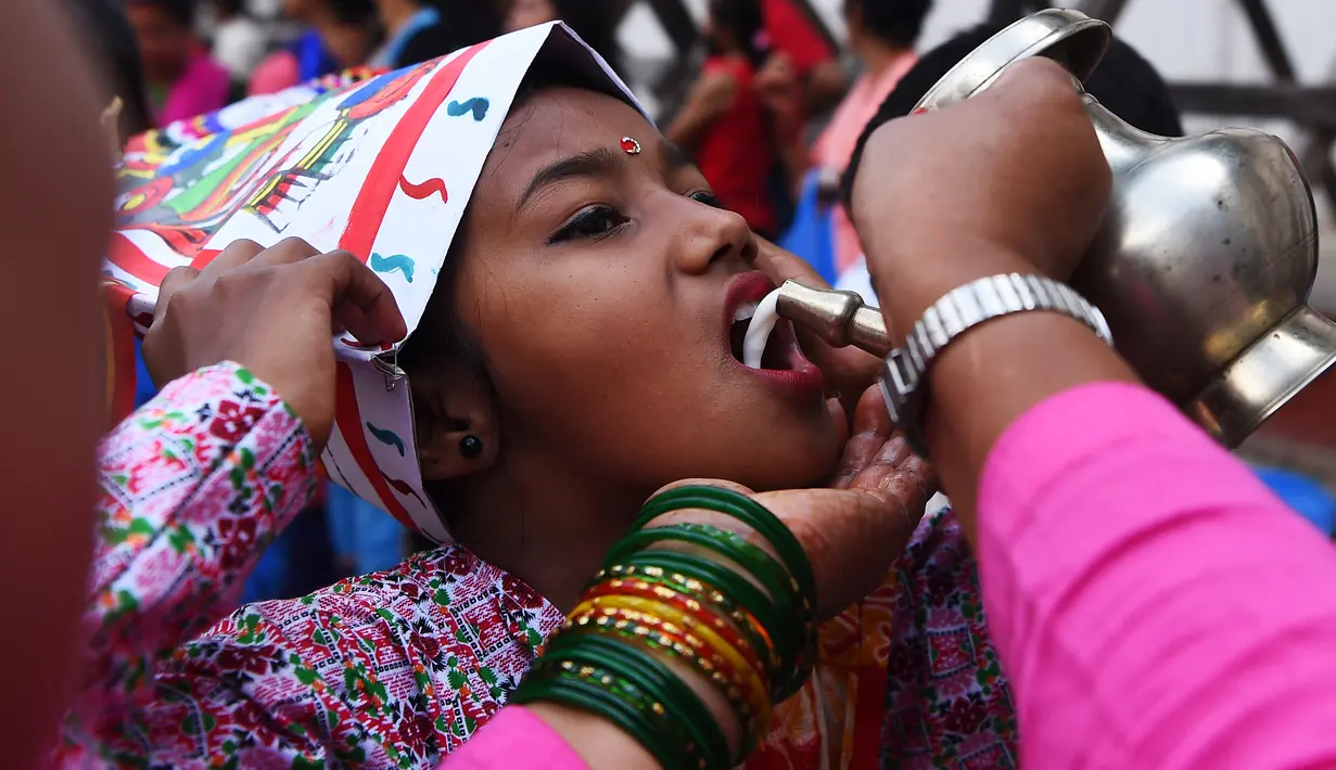Seorang anak Nepal meminum susu saat mengikuti Gai Jatra cow festival di Kathmandu, Nepal (8/8). (AFP Photo/Prakash Mathema)