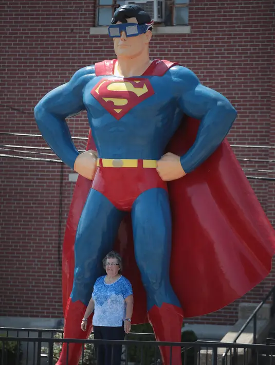 Warga berpose di bawah patung Superman di Metropolis, Illinois (18/8). Pada 21 Agustus mendatang, gerhana matahari total akan terlihat jelas di AS, tepatnya di pantai South Carolina sampai Oregon. (Scott Olson / Getty Images / AFP)