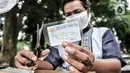 Feri (28) saat menyelesaikan jasa servis kartu tanda penduduk (KTP) di Jakarta, Kamis (21/1/2021). Harga servis dibanderol Rp 10.000 - Rp 20.000 per kartu, tergantung tingkat kesulitan perbaikan. (merdeka.com/Iqbal S. Nugroho)