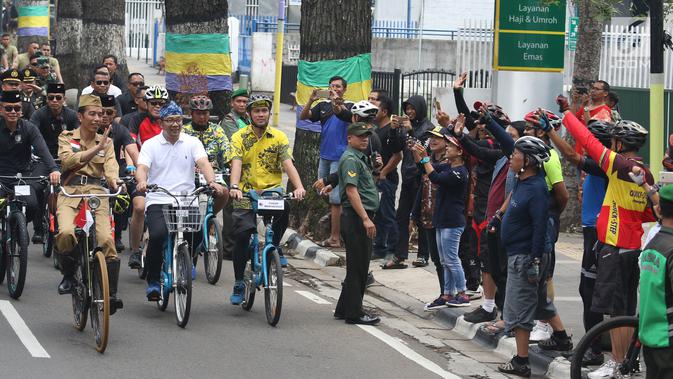 Presiden Joko Widodo atau Jokowi menyapa warga saat mengikuti Bandung Lautan Sepeda, Sabtu (10/11). Jokowi menaiki sepeda ontel dalam kegiatan tersebut. (Liputan6.com/Angga Yuniar)