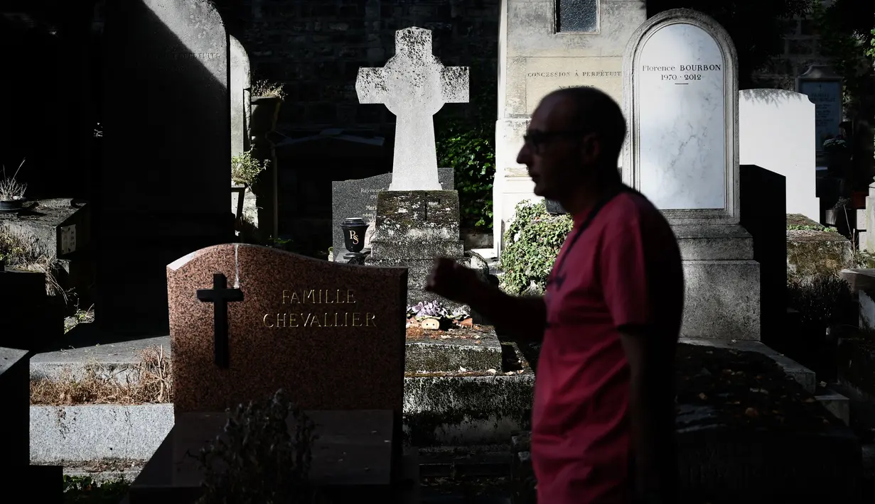 Seorang turis berjalan melewati kuburan di pemakaman Pere Lachaise di Paris (22/7/2019). Pemakaman ini jauh dari kata angker apalagi menyeramkan sebab setiap tahun ribuan bahkan jutaan wisatawan dari berbagai mancanegara berkunjung ke tempat ini. (AFP Photo/Philippe Lopez)