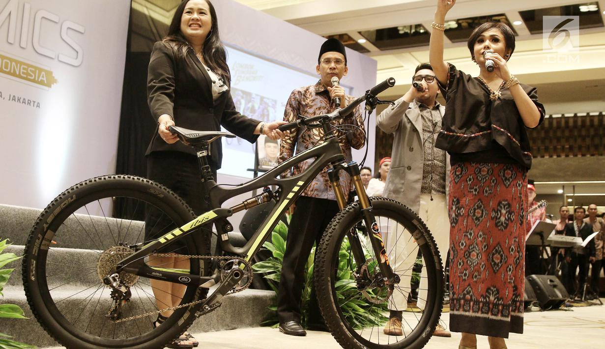 Gubernur NTB, TGB Muhammad Zainul Majdi bersama artis Yuni Shara melelang sepeda bekas Presiden Jokowi saat dipakai di Lombok pada acara penggalangan dana untuk Lombok-Sumbawa di Jakarta, Jumat (14/9). (Liputan6.com/Herman Zakharia)