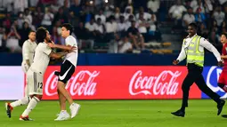 Seorang fans berusaha memeluk bek Real Madrid, Marcelo selama pertandingan semifinal Piala Dunia Antarklub 2018 antara Real Madrid melawan Kashima Antlers di stadion Zayed Sports City di Abu Dhabi, Uni Emirat Arab (19/12). (AFP Photo/Giuseppe Cacace)