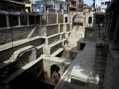 Orang-orang mandi di sumur tangga Bansilalpet berusia abad ke-18 yang sedang menjalani pekerjaan restorasi di Secunderabad, kota kembar Hyderabad, India (24/8/2022). (AFP/Noah Seelam)