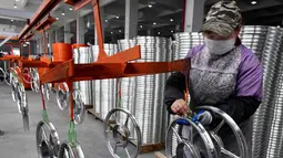 Seorang pekerja wanita mengecek kondisi pelek di pabrik pembuatan pelek sepeda motor di Jinhua, Provinsi Zhejiang, China (14/1). (AFP Photo/China Out)