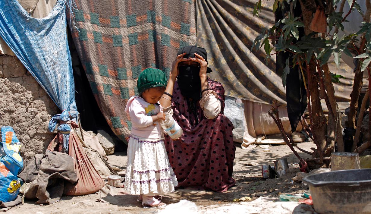 Seorang wanita bersama dengan putrinya di tenda kamp pengungsian di Dharawan, Sanaa, Yaman, (15/4). (AFP Photo / Mohammed Huwais)