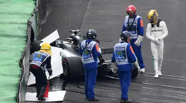 Pembalap Mercedes, Lewis Hamilton (kanan) melihat mobilnya usai menabrak saat kualifikasi F1 GP Brasil di sirkuit Interlagos di Sao Paulo, Brasil (11/11). Mobil Hamilton itu hancur sehingga bendera merah harus berkibar. (AFP Photo/Nelson Almeida)