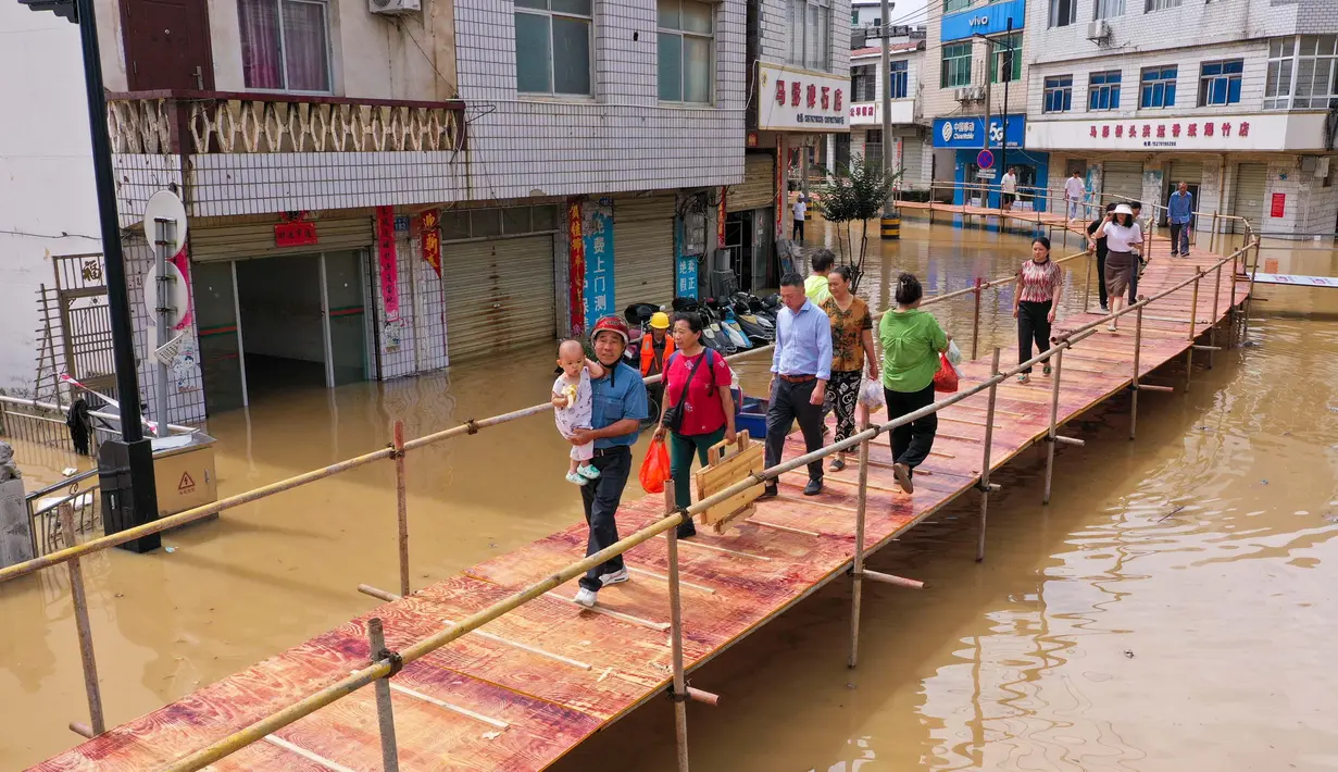 Jembatan yang membentang di atas genangan banjir memudahkan mobilitas warga dengan aman. (Foto: AFP)
