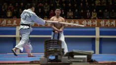 Seorang peserta saat dipukul dengan kayu selama demonstrasi taekwondo sebagai bagian dari Kejuaraan Seni Bela Diri Nasional tahunan Mangyongdae di 'Taekwon-Do Hall' di Pyongyang, Korea Utara (9/11). (AFP Photo/Kim Won Jin)