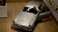 Staf berpose dengan Aston Martin DB5 yang digunakan dalam film James Bond GoldenEye tahun 1995 rumah lelang Bonham, London, Selasa (19/6). Hasil lelang tersebut bukan untuk amal, tapi untuk menambah pundi-pundi uang pemiliknya. (AP/Matt Dunham)