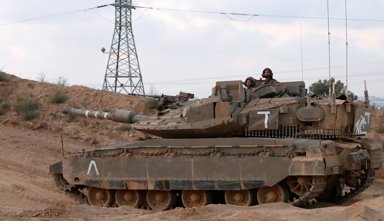 Tentara Israel mengendarai tank tempur Merkava di perbatasan dengan Jalur Gaza, Palestina, Jumat (20/7). Israel mengklaim serangannya dilakukan setelah tentaranya tewas dalam bentrok di perbatasan. (JACK GUEZ/AFP)