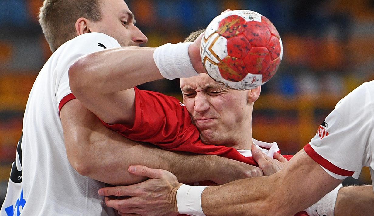 Pemain bola tangan timnas Polandia, Patryk Walczak (tengah mendapat perlawan dari pemain timnas Jerman dalam pertandingan  kejuaraan Bola Tangan Dunia 2021 di Kairo. (Foto: AFP/Pool/Anne-Christine Poujoulat)