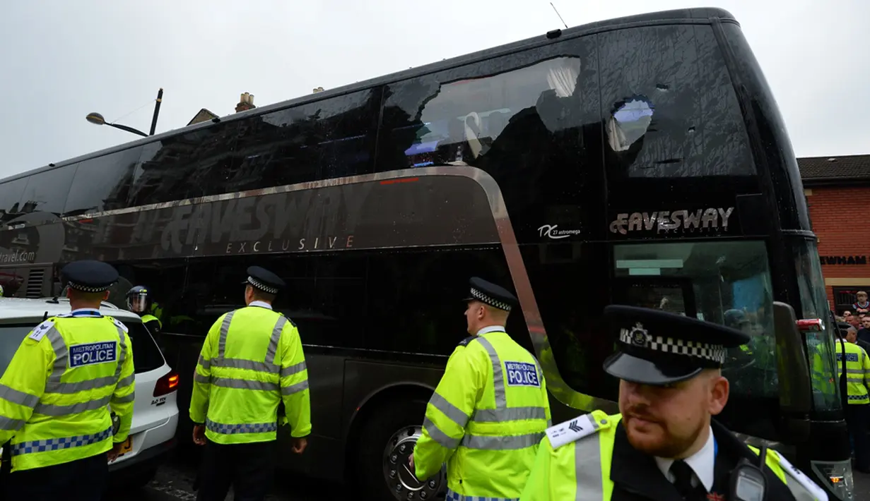 Polisi menjaga ketat bus Manchester United yang beberapa bagian kacanya pecah setelah dilempar oleh oknum suporter West Ham United. Rabu (11/5/2016) dini hari WIB. (AFP/Glyn Kirk)