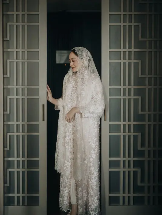 Nuansa lembut terwujud dari dominasi warna pink pada kain brokat modern dress Salsha yang memberi impresi feminin dan juga kalem. Terdapat juga detail beads yang disematkan pada tepian dress. Salsha kemudian memadukan dress-nya dengan matching veil dari ARTKEA CLASSIC. [@lacebyartkea/@salshabillaadr/@aaliyah.massaid].