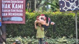 Seorang anak mengenakan kostum badut saat ikut dalam aksi di depan Balai Kota DKI Jakarta, Kamis (1/12/2022). Sebelumnya, PT JakPro mengatakan harga sewa Kampung Susun Bayam di dekat Jakarta Internasional Stadium (JIS) disesuaikan menggunakan Pergub Nomor 55 Tahun 2018. JakPro menyebut tarif tertinggi rusun tersebut Rp765 ribu per bulan. (merdeka.com/Iqbal S Nugroho)