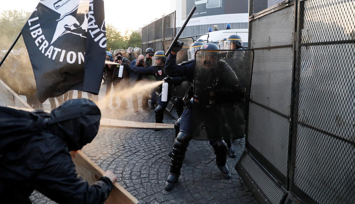 Pasukan anti-huru hara menyemprotkan caiaran kepada demonstran anti-fasis saat mereka menggelar aksinya di Paris (23/4). Bentrokan antara aparat dan demonstran ini terjadi usai pengumuman hasil perolehan suara Pemilu Prancis. (AFP/Thomas Samson)