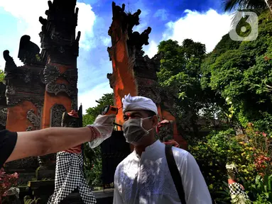 Petugas memeriksa suhu tubuh pengurus Pura Amerta Jati menjelang persiapan Hari Raya Nyepi Saka 1942 di Cinere, Depok, Selasa (24/3/2020). Rangkaian perayaan Nyepi di sejumlah pura hanya akan dilakukan oleh panitia dalam jumlah terbatas untuk mencegah penyebaran Covid-19. (merdeka.com/Arie Basuki)