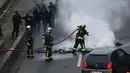 Pemadam kebakaran memadamkan api dari ban yang dibakar pengemudi taksi saat unjuk rasa menentang layanan transportasi VTC seperti Uber, di jalan lingkar di porte Maillot di Paris, Perancis, Selasa (26/1). (AFP PHOTO/Thomas SAMSON)