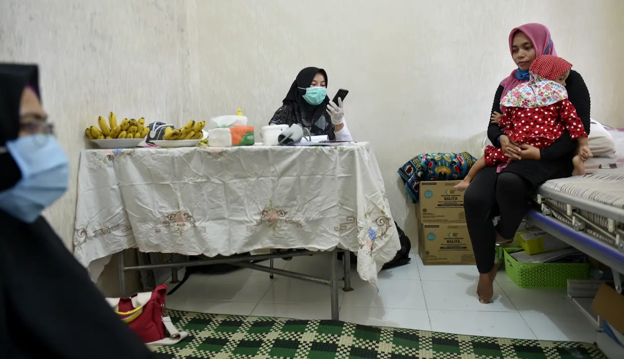 Seorang ibu dan bayinya menunggu untuk mendapatkan vaksin campak dan polio di sebuah posyandu di Banda Aceh, Aceh, Rabu (4/10/2020). Pemberian vaksin polio dan vaksin campak secara gratis yang berlanjut di tengah pandemi COVID-19 bertujuan memperkuat imunitas anak. (CHAIDEER MAHYUDDIN / AFP)