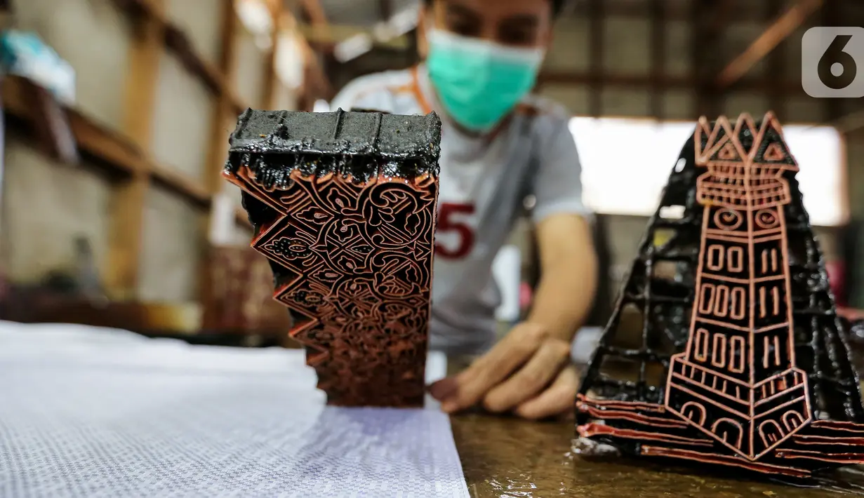 Perajin mencetak batik di rumah produksi batik tanah liek Ayesha Collection di Padang, Sumatera Barat, Kamis (25/11/2021). Batik tanah liek yang menggunakan tanah liat sebagai pewarna dasar direndam di dalam larutan tanah liat dalam jangka waktu tertentu. (Liputan6.com/Fery Pradolo)