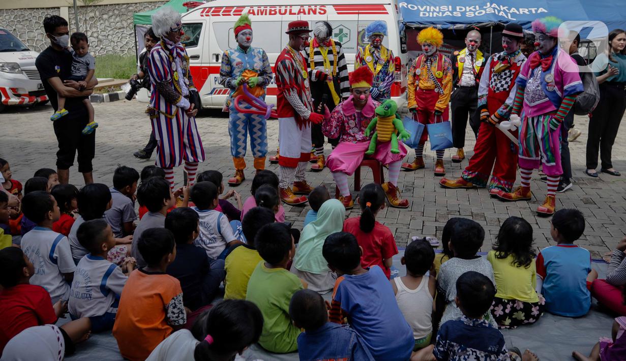 Anak-anak menyaksikan aksi badut yang tergabung dalam komunitas Aku Badut Indonesia (ABI) di pengungsian korban banjir di Gor Pangadegan, Jakarta, Selasa (7/1/2020). Trauma healing diberikan para badut sebagai bentuk kepedulian terhadap anak-anak korban banjir Jakarta. (Liputan6.com/Faizal Fanani)