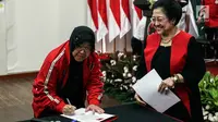 Ketua Bidang Kebudayaan DPP PDIP Tri Rismaharini Tri Rismaharini disaksikan Ketum PDIP Megawati Soekarnoputri menandatangani janji jabatan saat pelantikan di Jakarta, Senin (19/8/2019). Risma resmi menjabat sebagai Ketua Bidang Kebudayaan DPP PDIP masa bakti 2019-2024. (Liputan6.com/Johan Tallo)