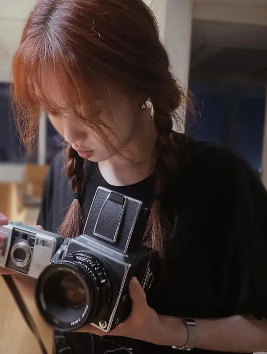 Momen saat Lee Sung Kyung sibuk mengoperasikan kamera analognya. Saat mengisi waktu luang pun perempuan tersebut mengenakan kaos oblong andalannya. (Instagram/@heybiblee)