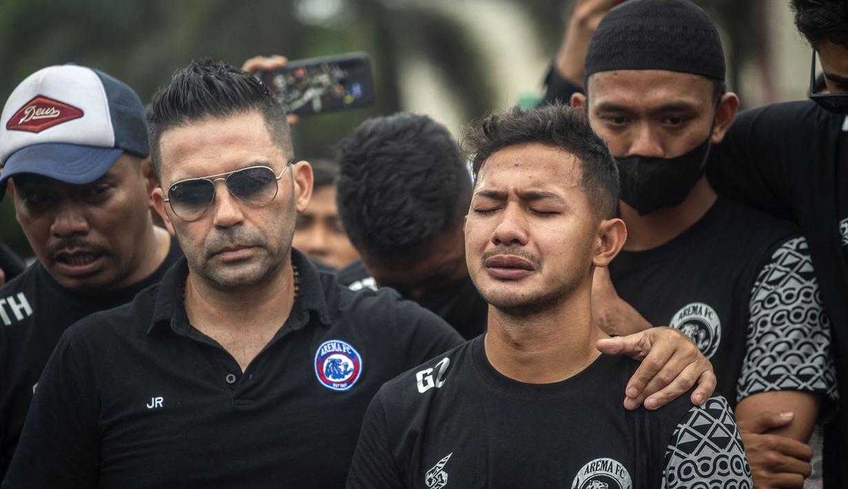 Javier Roca berusaha menenangkan Gian Zola (kanan) yang menangis saat tiba di Stadion Kanjuruhan. (AFP/Juni Kriswanto)