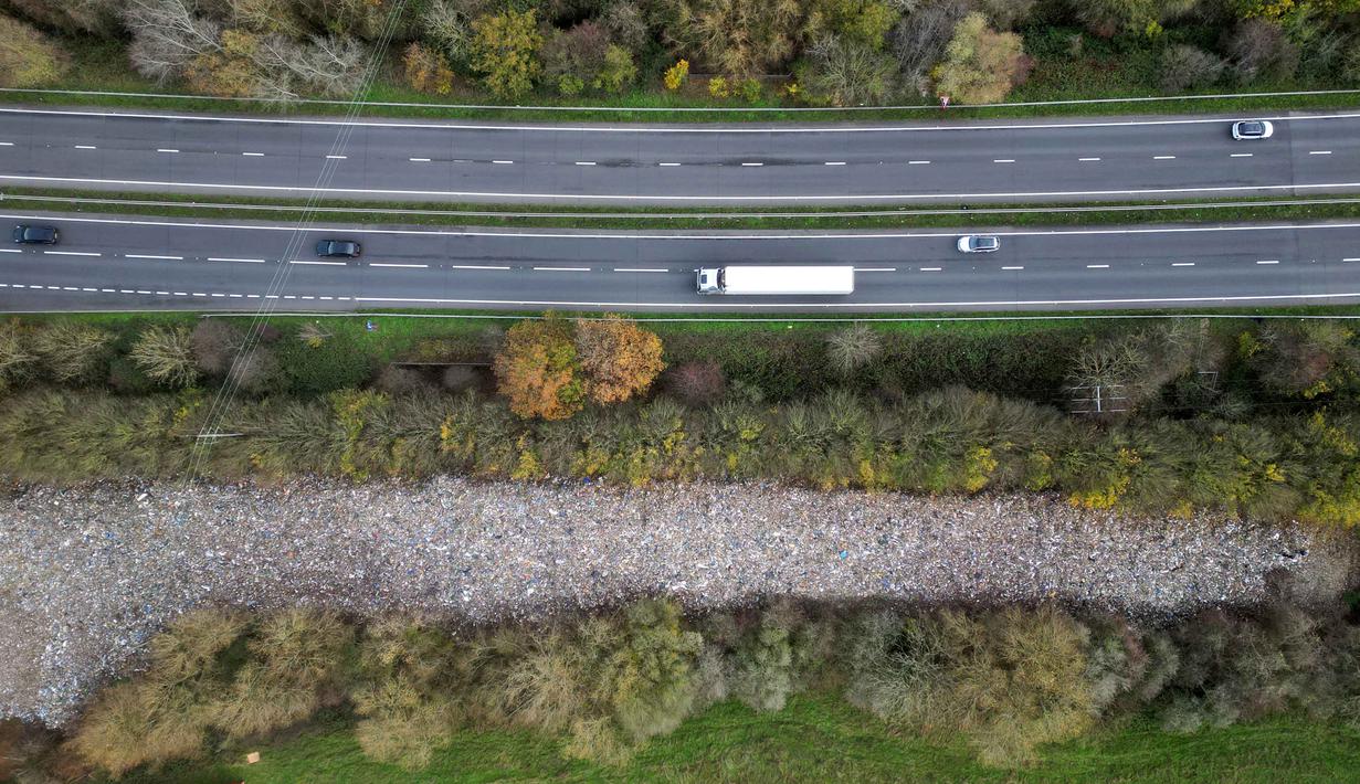 Diperkirakan, total berat dari tumpukan sampah tersebut mencapai ratusan ton. Tampak foto udara memperlihatkan tumpukan besar sampah yang dibuang sembarangan, yang dibuang di sebuah ladang antara Sungai Cherwell dan Jalan Raya A34 dekat Kidlington, Oxfordshire, di barat London pada 16 November 2025. (Justin TALLIS/AFP)