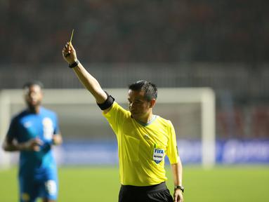 Wasit&nbsp;Xaypaseth Phongsanit memberikan kartu kuning&nbsp;saat laga FIFA Match Day antara Timnas Indonesia melawan Timnas Curacao di Stadion Pakansari, Bogor, Selasa (27/09/2022). (Bola.com/Muhammad Iqbal Ichsan)