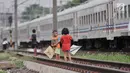 Anak-anak bermain layang-layang di rel kereta api kawasan Jakarta Timur, Kamis (3/1). Minimnya lahan terbuka hijau memaksa anak-anak setempat memilih kawasan rel kereta api sebagai lokasi bermain. (Merdeka.com/Iqbal Nugroho)