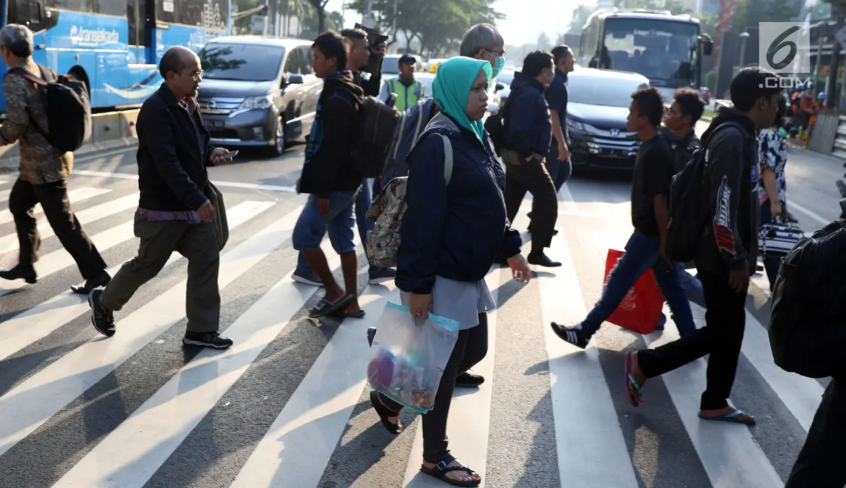 Warga melintasi Pelican Crossing di sekitar Halte Transjakarta Gelora Bung Karno, Jakarta, Jumat, (30/11). Ada tiga jembatan penyeberangan orang (JPO) di Jalan Jenderal Sudirman, Jakarta, yang sedang direvitalisasi. (Liputan6.com/Helmi Fithriansyah)