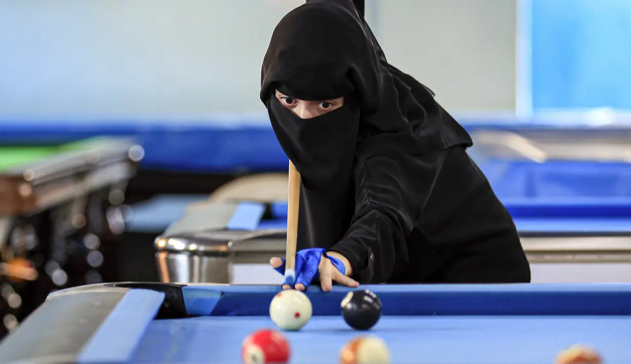 Seorang wanita membidik bola saat mengikuti kejuaraan biliar lokal di sebuah gedung olahraga di ibu kota  Sanaa, Yaman  (16/12/2019).  (AFP/Mohammed Huwais)