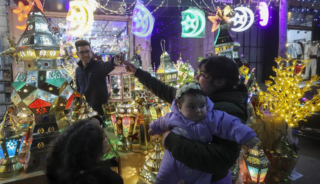 Warga Palestina berbelanja lentera tradisional "fanous" di Hebron di Tepi Barat yang diduduki pada 27 Maret 2022. Fanous merupakan lentera untuk dekorasi yang digunakan merayakan awal bulan suci Ramadan. (HAZEM BADER / AFP)