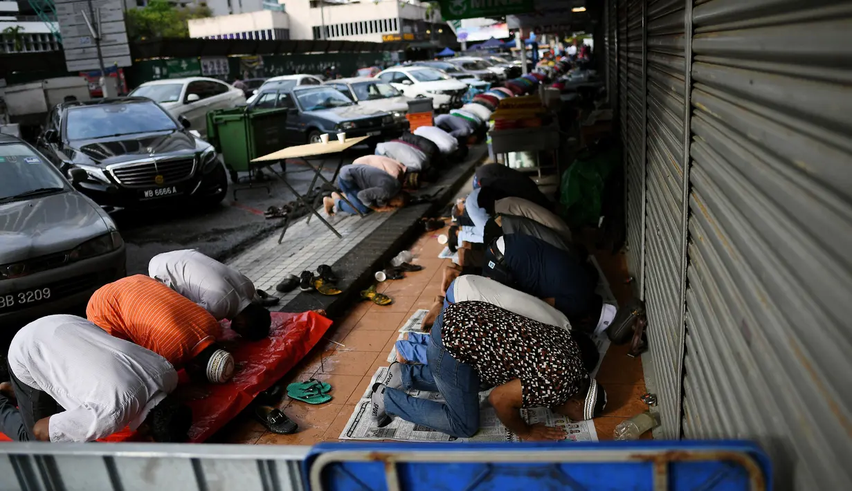 Sejumlah umat muslim Malaysia melakukan salat Idul Fitri di depan toko yang berada di sekitar Masjid India di Kuala Lumpur, Malaysia (25/6). (AFP Photo/Manan Vatsyayana)