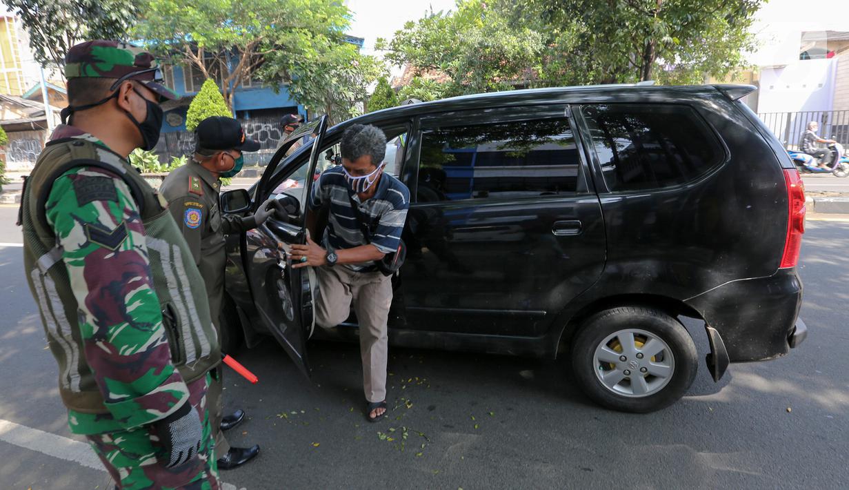 Petugas memindahkan penumpang yang duduk berdampingan dengan pengemudi mobil pada hari pertama PSBB di jalur check point Jalan Ir. H Juanda, Ciputat, Tangerang Selatan (18/4/2020). Status PSBB bertujuan untuk mengurangi jumlah penyebaran Covid-19 di wilayah Tangerang. (Liputan6.com/Fery Pradolo)