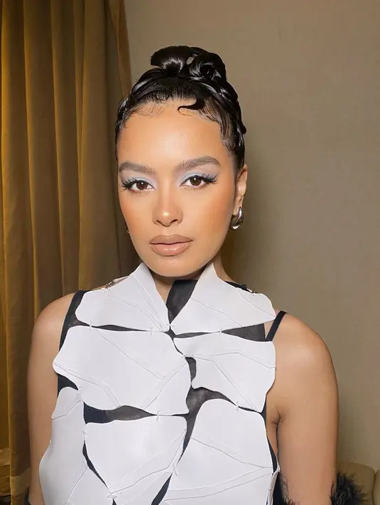 MUA Vagueskin tampak memberikan Y2K makeup look dengan sentuhan modern pada wajah Eva Celia. Bagian kelopak matanya diberikan eyeshadow nuansa icy blue. Sementara bibirnya, diaplikasikan lip gloss nuansa nude. [@vagueskin]